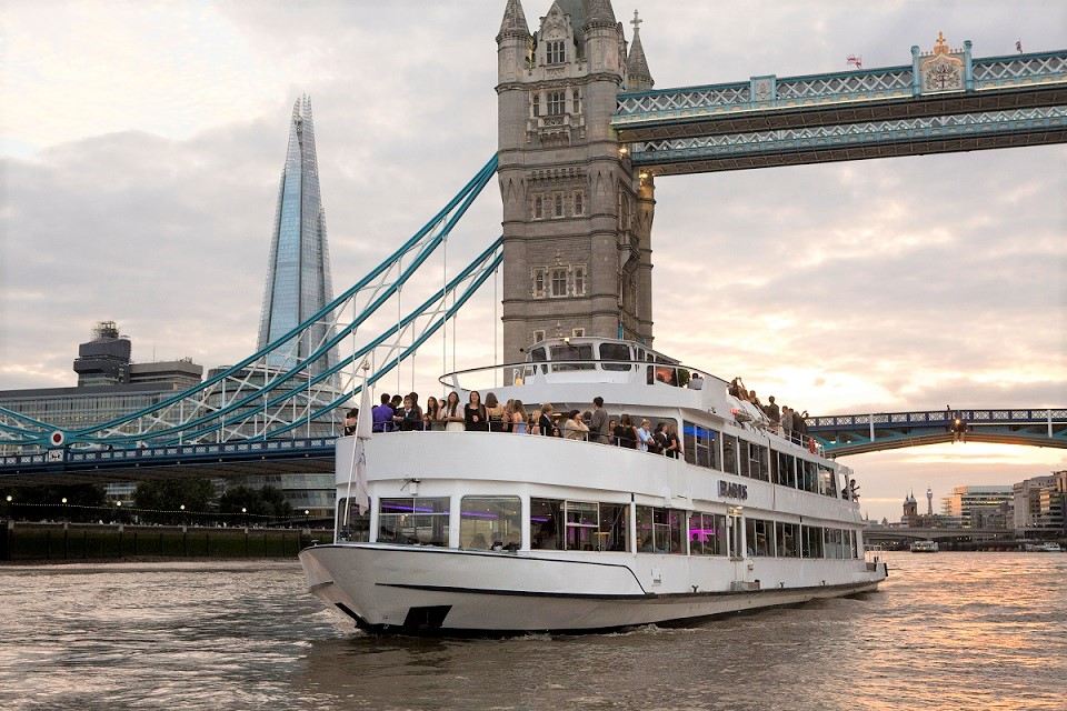 Thames Clippers river boat at Greenwich Pier with London skyline in background